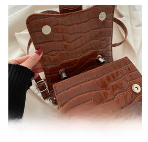 Détail macro du sac en cuir de crocodile marron avec fermoirs métalliques magnétiques