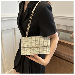 Detail of a beige tweed crossbody bag with gold chain and woven fabric texture