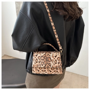 Détail du sac à bandoulière imprimé léopard porté avec une veste en cuir noir sur mannequin