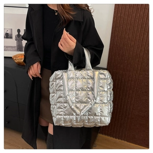 Silver quilted tote bag in metallic finish worn by model over a black winter coat