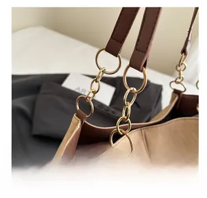 Détail des maillons de chaîne dorés et de la bandoulière en cuir sur un sac en toile