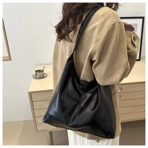 Model view of large black matte leather hobo tote bag worn over the shoulder in a lifestyle setting