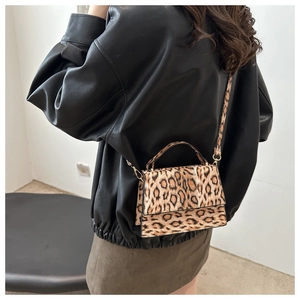 Détail d'un sac à bandoulière léopard porté avec une veste en cuir et une jupe