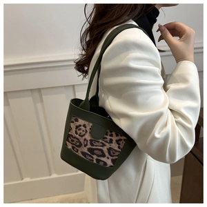Detail of leopard print bucket bag worn by model over shoulder on white blazer outfit
