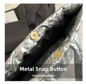 Détail du fermoir magnétique doré sur un sac cabas matelassé en argent brillant