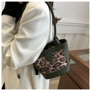 Detail of green bucket bag featuring leopard print panel and smooth leather texture