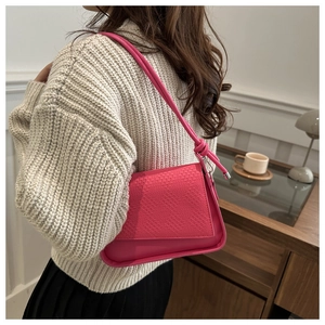 Detail of hot pink shoulder bag featuring woven embossed texture and knotted strap detail