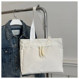 Close-up of a white canvas tote bag with decorative braided rope zippers and sleek design