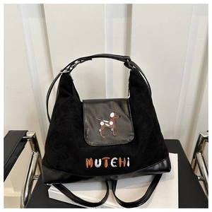 Detail of a black suede tote bag featuring a cute dog embroidery and smooth leather panel