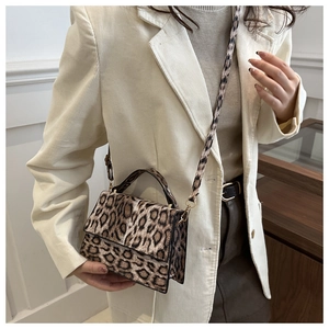 Détail du sac bandoulière léopard avec boucles dorées porté sur une veste en velours blanc