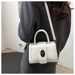 Sac à main blanc effet croco sur manteau gris, montrant le fermoir tournant métallique