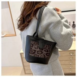 Side view of black bucket bag with leopard print panel worn on model shoulder