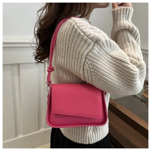 Close-up of pink shoulder bag with woven texture flap and knot detail on strap