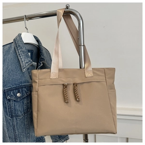 Close-up of khaki nylon tote bag with decorative rope zippers and wide shoulder straps