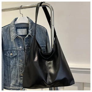 Close-up detail of a black leather Hobo bag with central stitching and glossy finish