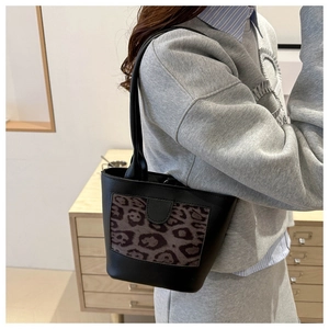 Detail view of stylish leopard print bucket bag carried on shoulder in home setting