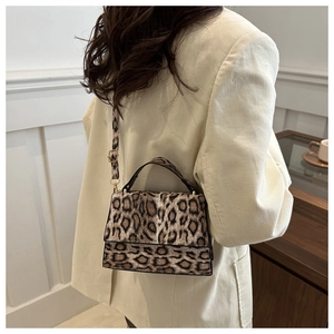 Détail d'un sac bandoulière à imprimé léopard porté par un mannequin chic