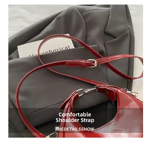 Close-up of burgundy leather crossbody bag with silver zipper and adjustable strap details