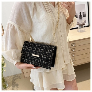 Detail of vintage black tweed crossbody bag with gold chain and metal hardware