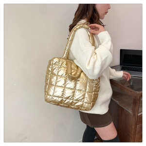 Detail of golden quilted tote bag showing metallic texture and reinforced padded handles