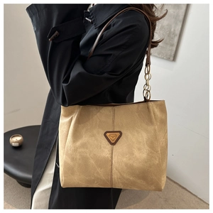 Détail du cabas en daim camel avec bandoulière en cuir et maillons de chaîne dorés