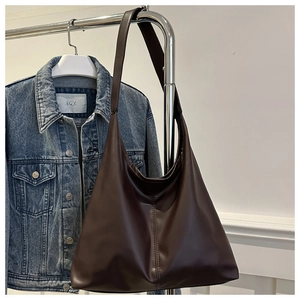 Close-up of a large dark brown leather tote bag with soft matte texture and wide shoulder strap