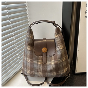 Détail macro du tissu à carreaux rétro et rabat en cuir avec boucle en métal N du sac