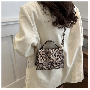 Gros plan du sac bandoulière vintage léopard avec boucles dorées sur une veste beige