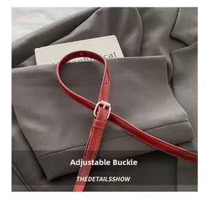Detail of adjustable deep red lizard-pattern leather strap with silver metal buckle