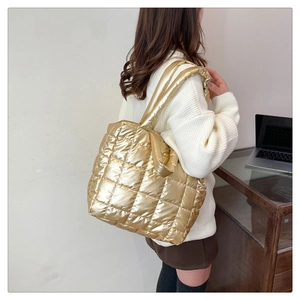 Macro detail of the golden quilted tote bag with metallic finish and soft shoulder strap