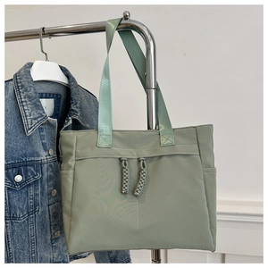 Detail of light green nylon tote bag featuring double braided drawstrings and side pockets