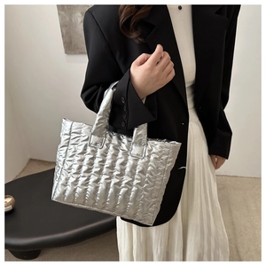 Détail du sac cabas matelassé argenté porté avec une tenue de mode moderne et minimaliste