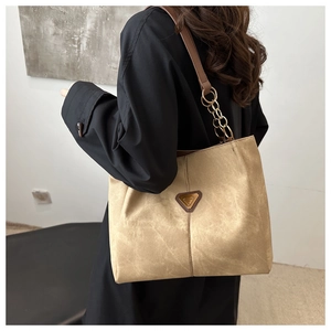 Détail du sac cabas kaki avec logo métallique vintage et bandoulière en chaîne dorée chic