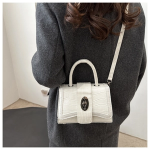 Détail du sac blanc motif crocodile avec élégant fermoir rotatif ovale en métal brillant