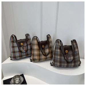 Détail de sacs cabas à carreaux bleu, marron et gris avec rabat en cuir et boucle dorée