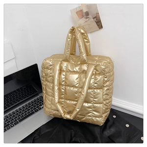 Detail of gold quilted puffer tote bag showing padded texture and dual handles
