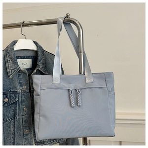 Close-up of light blue tote bag with decorative zippers and durable woven handles