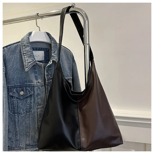 Detail of minimalist two-tone black and brown faux leather tote bag hanging on a rack