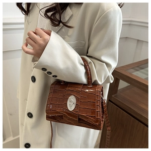 Sac bandoulière marron à motif crocodile et fermoir métallique porté avec blazer crème