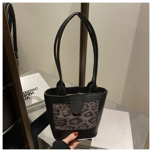 Close-up of black leather bucket bag with a leopard print pocket and slim double handles