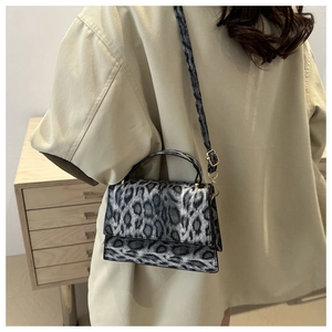 Détail d'un sac bandoulière léopard porté avec un manteau beige, style minimaliste