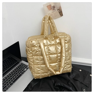Detailed macro view of gold quilted pattern texture on a large metallic tote bag