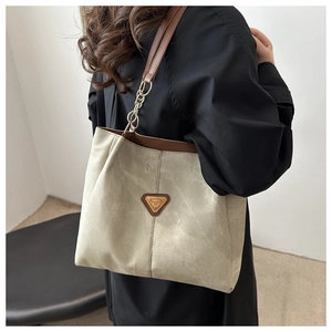 Détail d'un grand sac cabas avec bandoulière en cuir marron et logo sur tissu olive doux