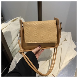 Detail of caramel leather woven flap and metallic buckle on this modern crossbody bag