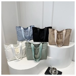 Detail of five colorful minimalist tote bags on a display stand with braided zipper pulls