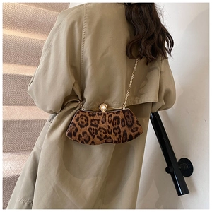 Détail de la pochette léopard avec fermoir perle et chaîne dorée sur un trench-coat