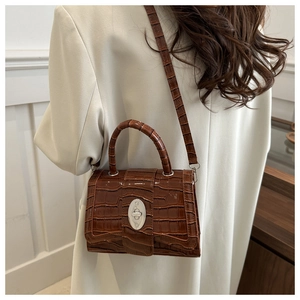 Sac bandoulière marron à motif crocodile avec fermoir rotatif argenté sur blazer beige
