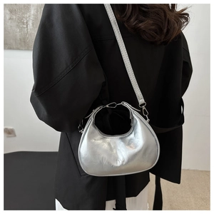Detailed back view of a silver metallic crescent bag worn crossbody on a black outfit