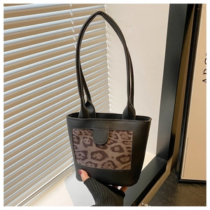 Close-up of black handbag featuring leopard print panel and shoulder strap detail