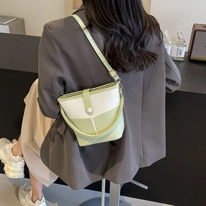 Green and white bucket bag with thin shoulder strap shown in a stylish interior setting